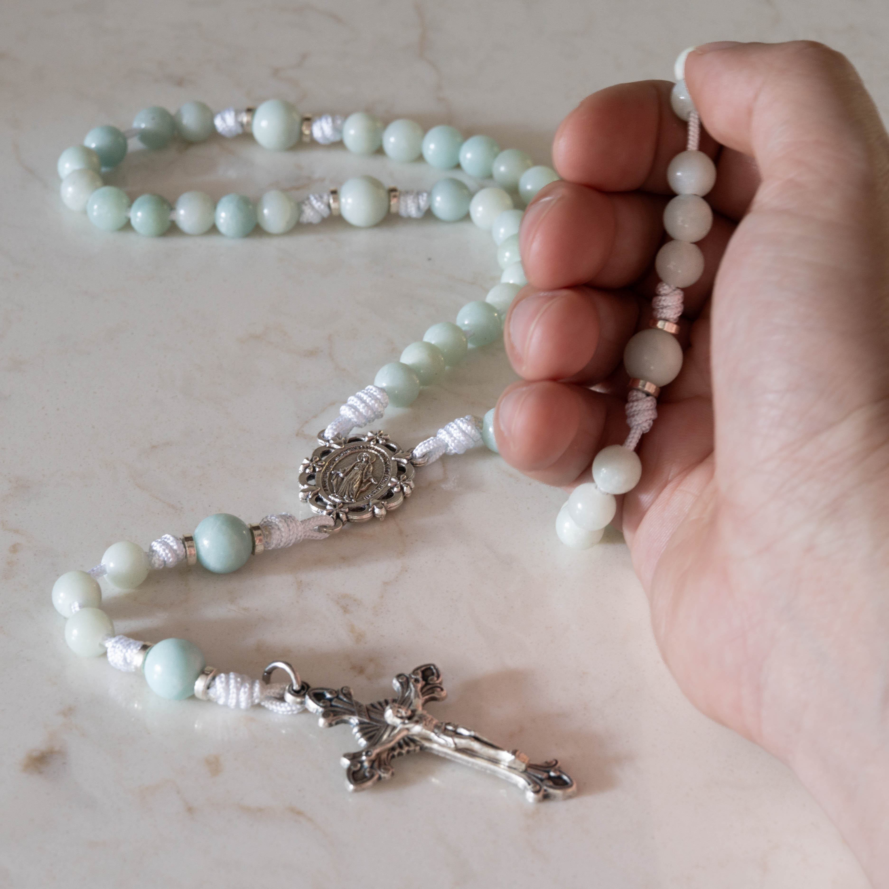 Star of the Sea gemstone rosary held in hand over a marble surface