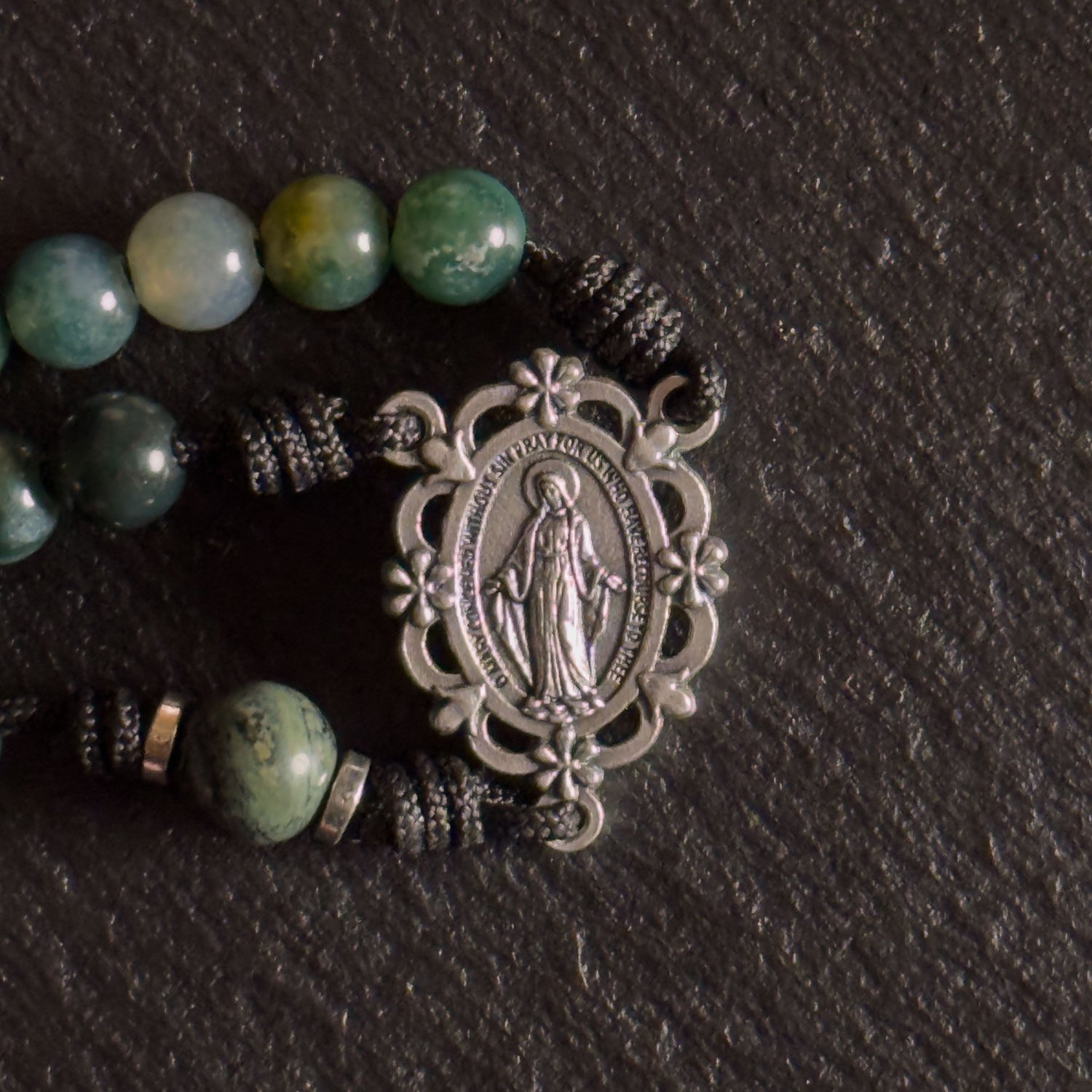Classic Catholic rosary collection with natural stone beads and crucifixes beside a leather Bible