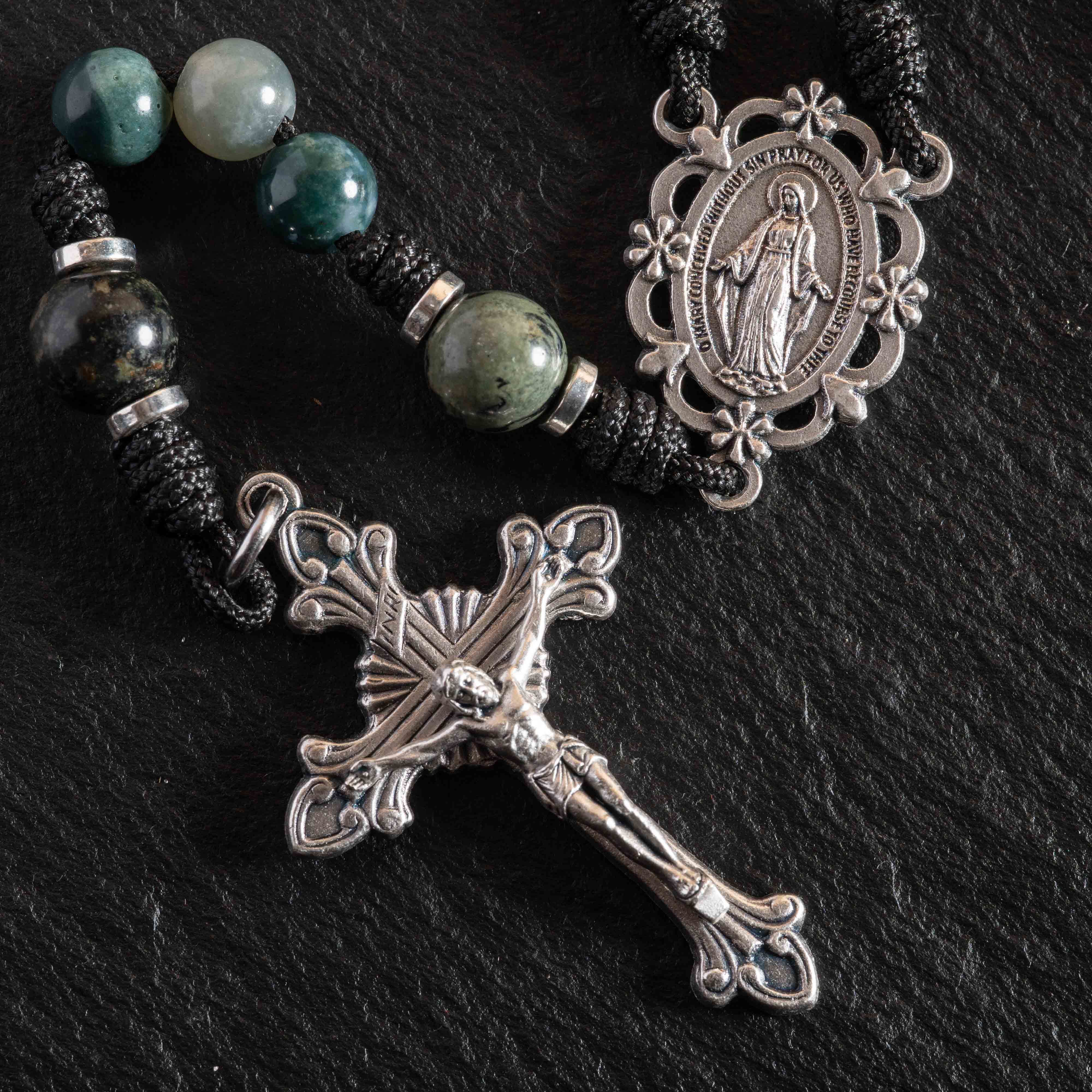 Classic Catholic rosary collection with natural stone beads and crucifixes beside a leather Bible